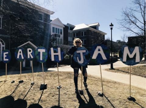 Plymouth State in 150 Objects exhibition 2010s student posing with earth jam celebration signs and 
