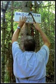 A Shelburne Trails Club volunteer placing a sign marking the newly opened spur trail to the Bald Cap Ledges