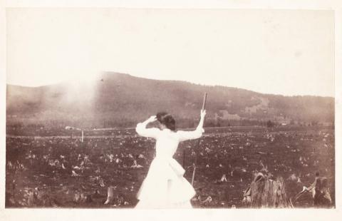 Woman standing and looking out in Jefferson 1885 with stumps and smoke around her