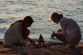 Campers sitting next to a lake