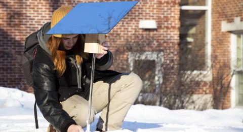 Student setting up scientific equipment outside. Hands-on activities aid in student satisfaction and retention.