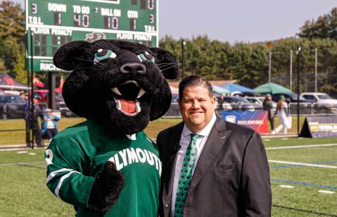 Photo of PSU panther mascot standing on a sports field with a man, Todd Angilly, in a suit and tie 