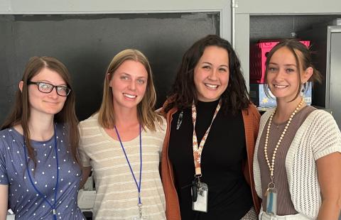 Four individuals pose for a photo, smiling.